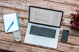 laptop, notebook, and phone on table.