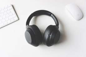 black headphones near white keyboard and computer mouse.